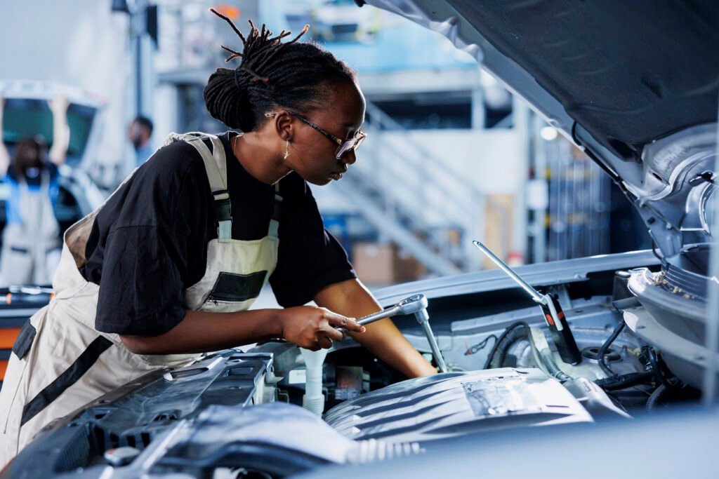 worker examines out of order car engine